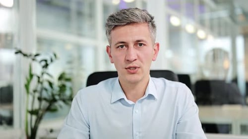 Businessman Speaking Directly to Camera in Bright Office for a Video Call