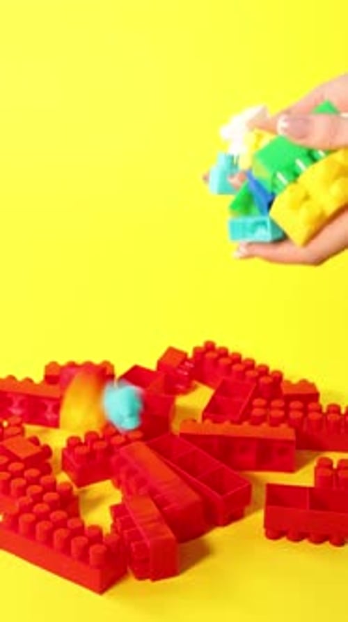 Mujer con bloques de construcción coloridos sobre fondo amarillo, primer plano