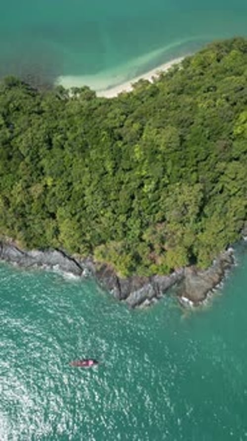 Vertical Video Drone Shot of a Sailboat Near a Tropical Island Shore with Coastal Cliffs