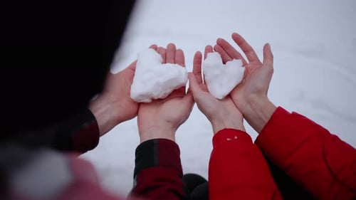 Romantic Hands Holding Snow Hearts on Snowy Day