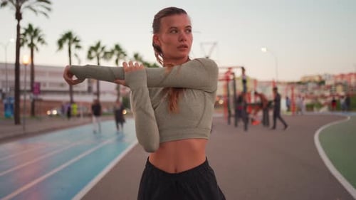 Woman Stretching Arms in City Park at Sunrise