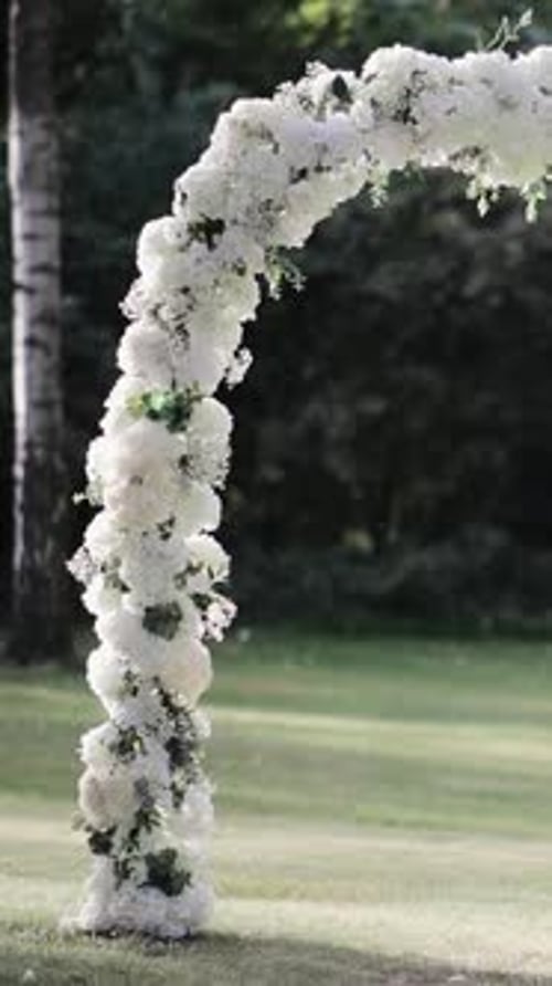 Place for bridal ceremony against the background of park garden backyard. Wedding arch with bouquets