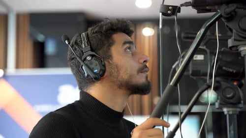 Cameraman with Professional Camera and Headphones Indoors