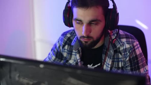 Young Man Wearing Gaming Headset Looking at Monitor