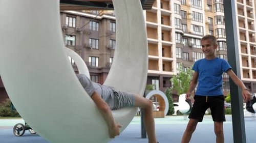 Children Playing on a Crescent Swing in Urban Park
