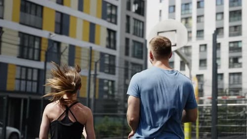 Athletes From the Back A Man and a Girl Play Sports on a Basketball Court