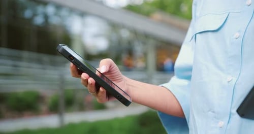Close-up of a woman s hand swiping on a smartphone outdoors, using the screen to browse or text, sho