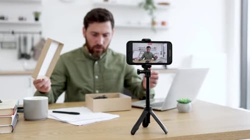 Man Unboxes Package While Recording with Phone