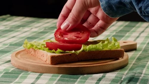 Preparing a Sandwich with Lettuce, Tomato, and Ham