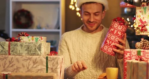 Young Man Examines Christmas Gifts With Tablet