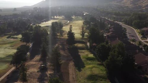 A golf course early morning with the sun shining over the course with green grass and trees.
A grou