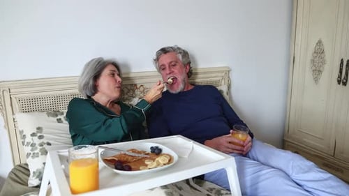 Loving Senior Couple Enjoying Breakfast in Bed Together