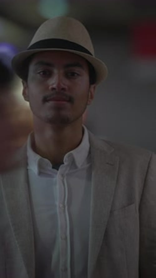 A Stylish Man Wearing a Hat and Suit Surrounded By Vibrant Urban Lights in the City