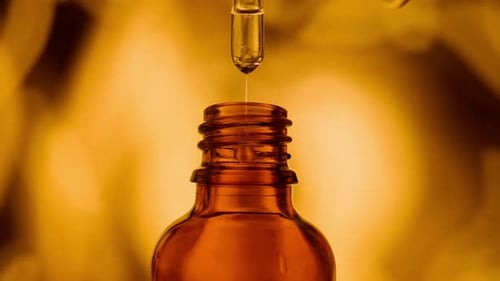 Dropper Adding Liquid to Amber Glass Bottle