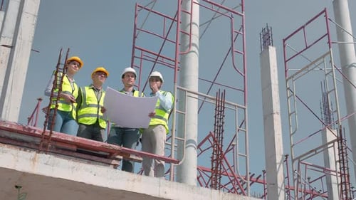 Teamgruppe aus Auftragnehmer und Architekt mit Vorarbeiter, die das Bauprojekt erläutern.