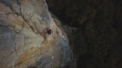 Adult Climbing Sheer Rock Face on Sunny Day