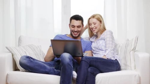 Couple relax together on couch with laptop