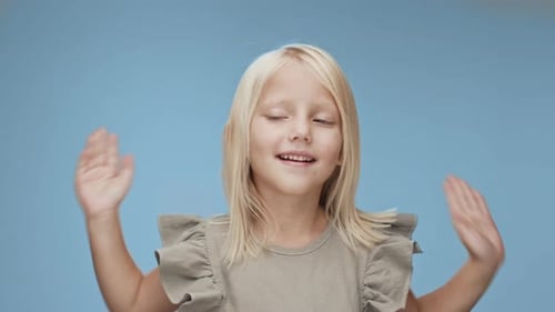 Smiling Girl Covering her Eyes on Blue Background