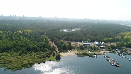 Dense Woodland Stretches Along Wide Body of Water Aerial View