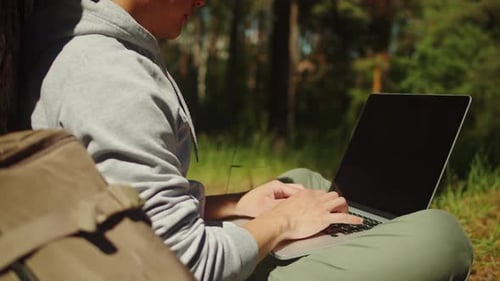 Man Works on Laptop in Green Forest Setting