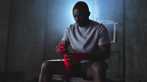 Fitness Workout in Gym African American Man Fighter Preparing for Fight Wrapping Hands with Red