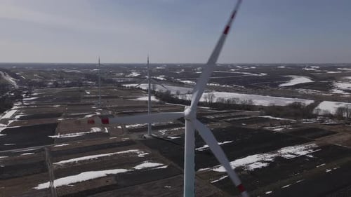 Aerial Close Up View on Three Wind Turbine Working in the Field at Winter Drone Flies Backward