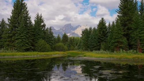 Timelapse de nuages se déplaçant au-dessus de la montagne et de la forêt, scène reflétée dans l'eau du lac