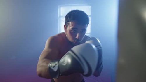 A Boxer Trains Punches By Punching a Punching Bag in a Training Hall