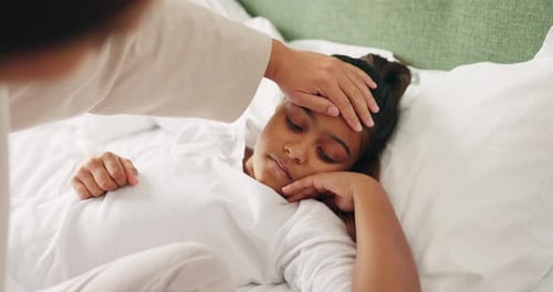 Checking Forehead of Young Adult Lying in Bed