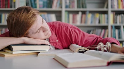 Tired Student Sleeping on Books in Library