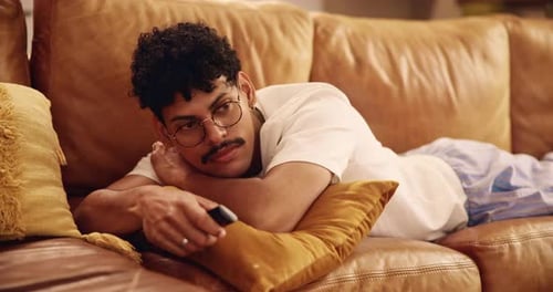 Young Adult Relaxing on Couch with Remote