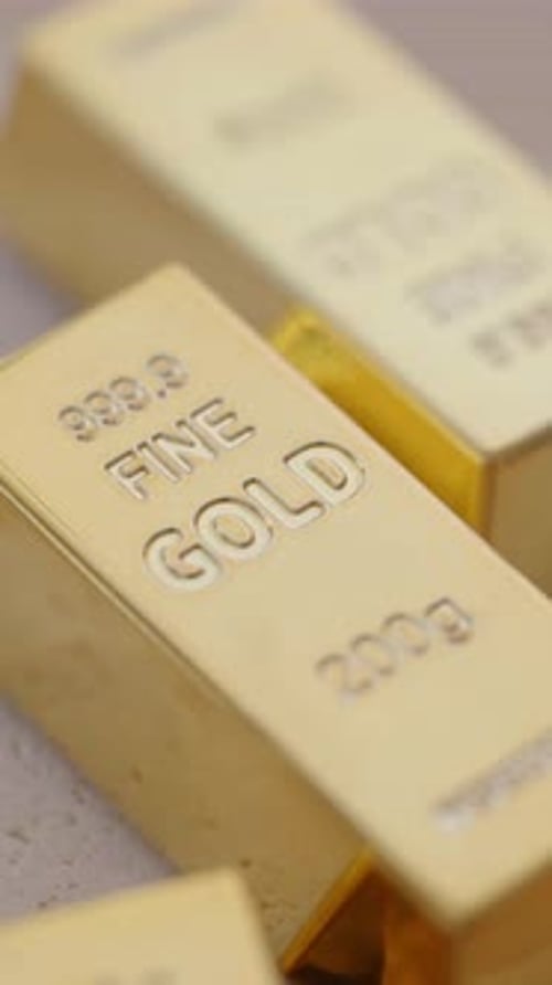 Goldbarren gestapelt auf einem Tisch in einem hellen Raum
