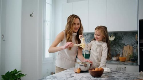 Woman and Girl Baking Together in White Kitchen