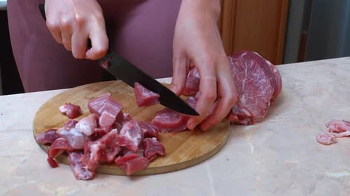 Female Cook Carefully Trims Fat And Dices Meat On Kitchen Counter