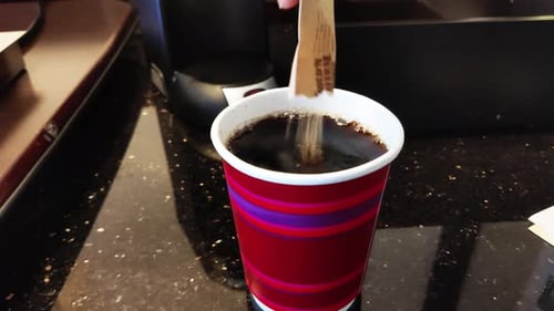 Adding Sugar to Coffee in Red Paper Cup