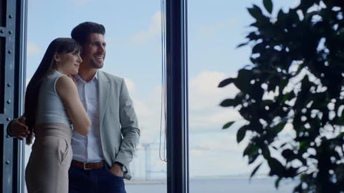Affectionate couple enjoying ocean view at hotel window during summer honeymoon