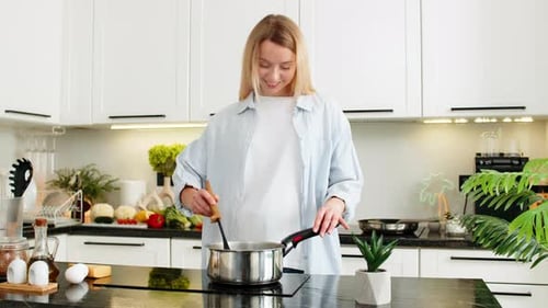 Woman Stirs Sauce in Modern Bright Kitchen