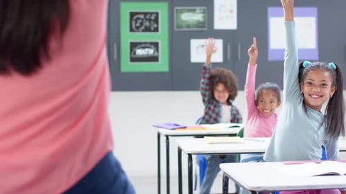 In school classroom, raising hands and smiling, students participating in lesson