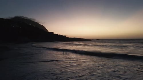 a couple playing with big waves at Sea over white sands of South African beach sunset time- aerial s