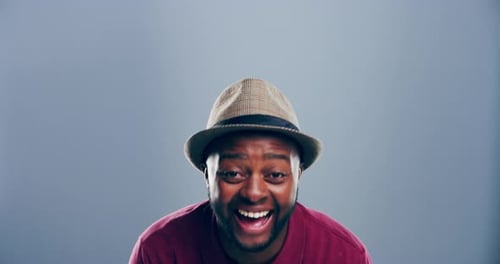4k video footage of a young man laughing against a grey studio background