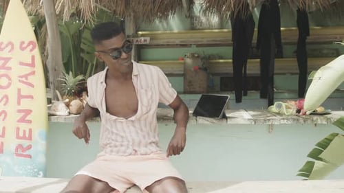 Man Sits at Tiki Hut on Tropical Beach