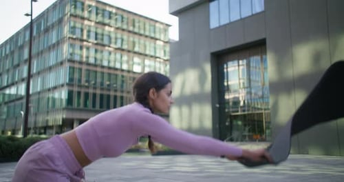 Active Woman Rolling Out Yoga Mat in City