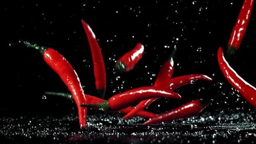 Rote Chilischoten fallen auf den Tisch, gefilmt mit einer Hochgeschwindigkeitskamera mit 1000 Bildern pro Sekunde