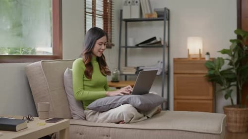 Woman wears green sweater working studying and liniving at home.