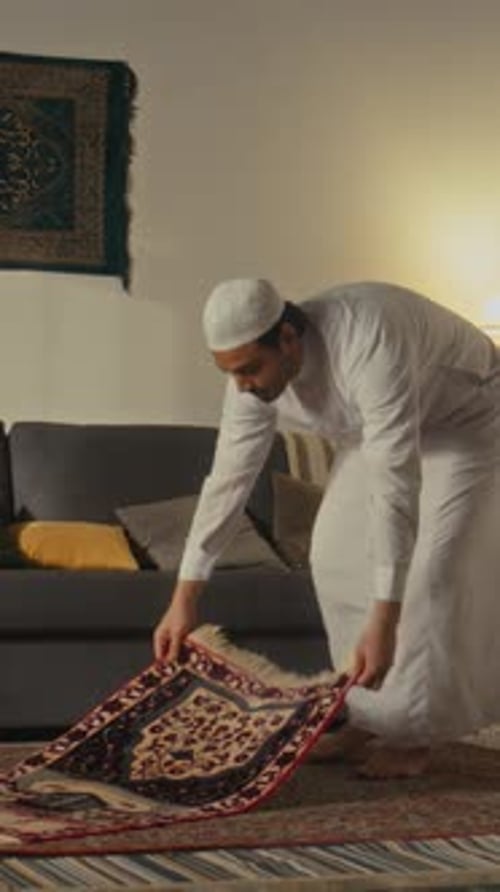 Vertical of Muslim Worshipper Beginning Praying on Mat at Home
