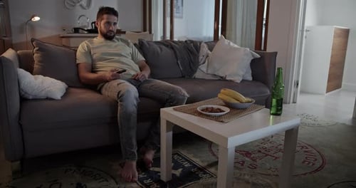 Man Relaxing on Sofa Watching Television Indoors