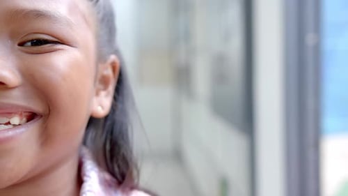 Criança sorridente mostrando felicidade e entusiasmo no corredor da escola, espaço de cópia