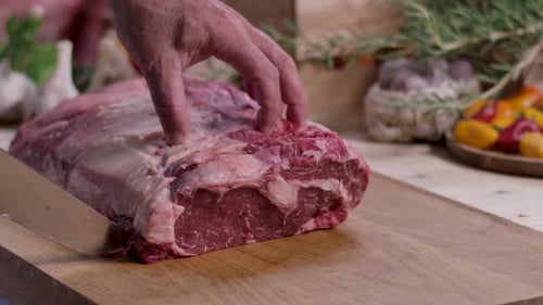 Man Cutting Raw Steak on Wooden Cutting Board