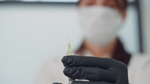 Masked Medical Worker Prepares Syringe for Injection