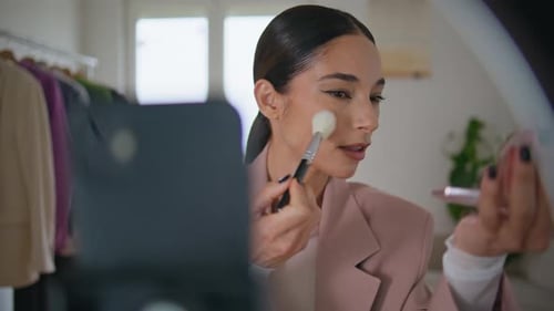 Woman applies makeup in front of camera